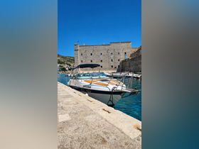 A sleek speedboat docked in a picturesque harbor, showcasing its elegant design against a backdrop of historic architecture.