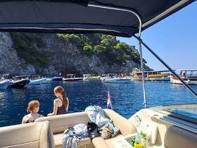 Two girls enjoy a sunny day on a boat, surrounded by other vessels in a picturesque bay — a perfect family outing for swimming and relaxation.
