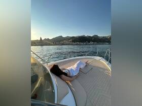 A woman relaxes on the deck of a boat, enjoying the serene sunset and picturesque coastal scenery — a perfect moment for unwinding on the water.
