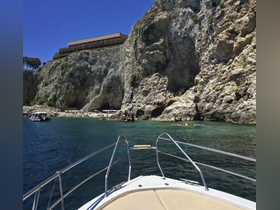 A stunning view from the bow of a boat, showcasing a rocky coastline and clear turquoise waters — perfect for exploring hidden coves and enjoying the beauty of nature.