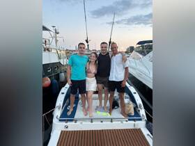 A group of friends poses together on the back of a boat, capturing a fun moment at the marina — perfect for memorable outings and celebrations on the water.