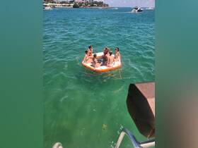 A lively group enjoys a fun day on a floating mat in the clear turquoise waters, perfect for summer parties and relaxation on the water.