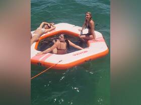 A group of friends enjoys a sunny day on a floating mat in the water, perfect for relaxation and fun in the sun.