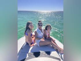 A joyful family enjoys a sunny day on the boat, capturing a perfect moment of togetherness against a sparkling ocean backdrop.