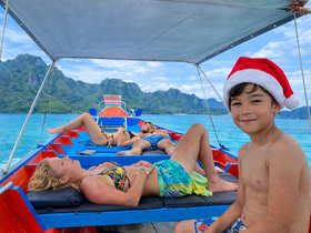A joyful scene aboard a boat with a family relaxing in tropical waters, featuring a child in a Santa hat — perfect for capturing memorable moments on a sunny day.