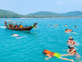 A vibrant scene of snorkelers enjoying the clear waters, with a traditional boat nearby, perfect for a fun day of aquatic adventures.