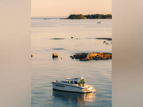 A serene view of a motorboat anchored in calm waters, surrounded by rocky outcrops and distant islands, perfect for showcasing tranquil boating experiences.