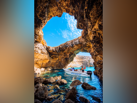 A group explores a stunning cave while aboard a boat, surrounded by crystal-clear waters — a perfect adventure for nature lovers and explorers.