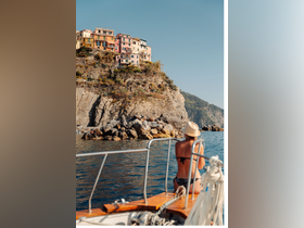 A woman enjoys the stunning coastal views of Cinque Terre from her boat, capturing the vibrant colors of the hillside homes and the serene waters — a perfect moment for adventure seekers.