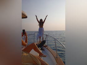 A joyful moment captured on a boat as a woman celebrates with arms raised, embodying the spirit of fun and adventure on the water.
