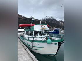 A beautifully docked fishing boat named 'Oh Whale' with a scenic mountain backdrop, perfect for fishing trips in Alaska.