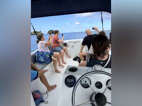 A lively group enjoys a boat ride, capturing memories with their phones while taking in the beautiful ocean views. Perfect for social outings and adventure on the water.