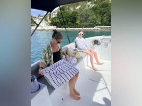 A mother and daughter relax on a boat, enjoying a sunny day by the water with towels in hand — perfect for family outings and leisure time on the sea.