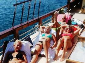 A group of friends relaxes on the deck of a boat, soaking up the sun and enjoying a day on the water — perfect for summer getaways and leisure trips.