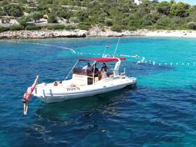 A child joyfully jumps off a boat into the crystal-clear waters, capturing the essence of summer fun and family adventures on the water.