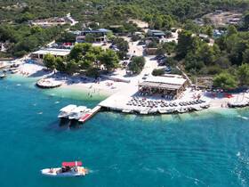 A vibrant beach scene featuring people enjoying the sun and water, with boats anchored nearby — a perfect destination for relaxation and fun on the water.