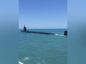 A submarine navigates through clear waters, showcasing its sleek design and operational capabilities — a rare sight for maritime enthusiasts.