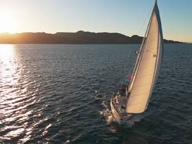 A stunning aerial view of a sailboat gracefully navigating the waters at sunset, showcasing the beauty of sailing adventures.