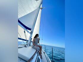 A woman enjoys a refreshing drink while relaxing on the deck of a sailboat, surrounded by the serene ocean — an ideal moment for sailing enthusiasts seeking tranquility on the water.