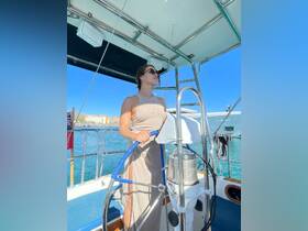 A woman confidently steers the helm of a sailboat, showcasing the stylish interior and inviting atmosphere perfect for a day on the water.