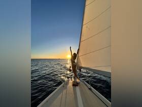 A joyful moment captured as a woman celebrates at sunset on a sailboat, embodying the spirit of adventure and relaxation on the water.