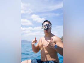 A young man poses with a snorkel mask, ready for an exciting snorkeling adventure in the clear blue ocean, showcasing the thrill of underwater exploration.