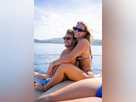 A joyful couple enjoys a sunny day on a yacht, embracing each other with smiles — perfect for romantic getaways or special celebrations on the water.