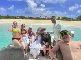 A joyful group of friends and family enjoys a sunny day at the beach, capturing memories aboard their boat — perfect for summer adventures and family outings.