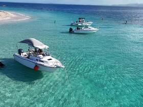 A scenic view of boats anchored in crystal-clear turquoise waters near a sandy beach, perfect for a day of relaxation and exploration.