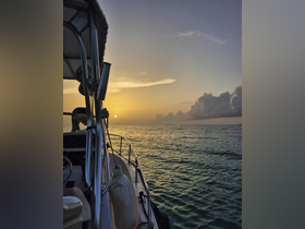 A serene sunset view from the deck of a boat, showcasing the tranquil waters and the silhouette of a person enjoying the evening — perfect for sunset cruises.