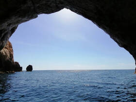 A stunning view from inside a cave looking out over the tranquil ocean, showcasing the natural beauty of coastal landmarks.