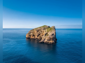 A stunning aerial view of a rocky island surrounded by deep blue waters, showcasing the natural beauty of coastal landscapes — perfect for adventure seekers and nature lovers.