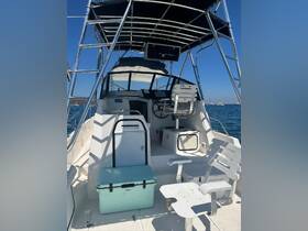 An inviting view of the helm area inside a boat, featuring seating and a cooler, perfect for a day on the water.