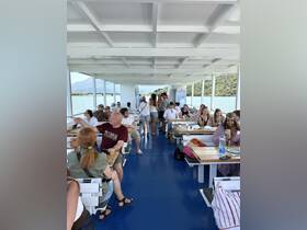 Inside view of a spacious boat cabin filled with guests enjoying their time, showcasing the comfortable seating arrangements and scenic views through the windows.