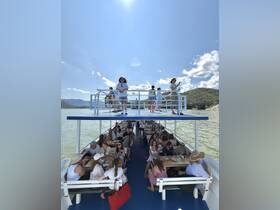 A lively group enjoys a dining experience aboard a boat, with guests socializing and taking in the scenic views — perfect for gatherings and celebrations on the water.