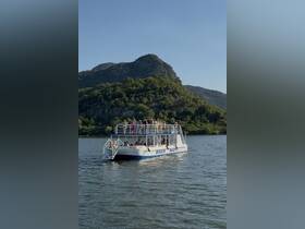 A lively group enjoys a boat trip, celebrating together on the water with stunning mountain views in the background.