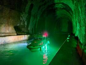 A boat navigates through a stunning cave illuminated by green lights, showcasing a unique and adventurous setting for exploration.