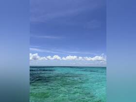 A serene view of turquoise waters under a clear blue sky, perfect for showcasing the beauty of tropical destinations.