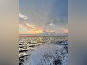 A stunning sunset over the water, with waves splashing in the foreground, creating a picturesque scene perfect for evening boat trips.