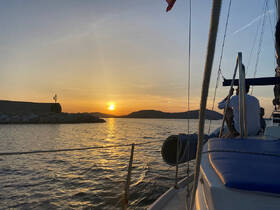 A serene sunset view from a sailboat, capturing a couple enjoying the tranquil waters — an ideal setting for romantic sailing adventures.