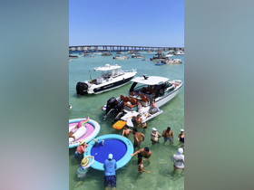 A lively scene at a sandbar with groups of people enjoying the water, floating mats, and multiple boats in the background — perfect for summer fun and social gatherings on the water.