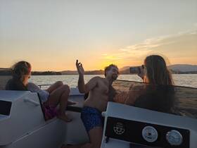 A group enjoys a sunset on a boat, capturing the moment on their phones — a perfect setting for memorable boating experiences.