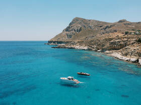 A stunning aerial view of two boats anchored in crystal-clear turquoise waters, surrounded by a picturesque coastline — perfect for exploring hidden coves and enjoying the beauty of nature.
