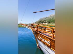 A stunning view of the bow of the 'Lorena' boat, showcasing its elegant wooden craftsmanship against a serene water backdrop, perfect for scenic cruises.