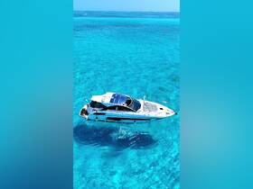 A stunning aerial view of a sleek yacht cruising through crystal-clear turquoise waters, perfect for luxury charters and island adventures.