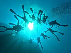 A dynamic underwater scene featuring a group of divers exploring the ocean depths, showcasing the beauty of marine life and the thrill of scuba diving.