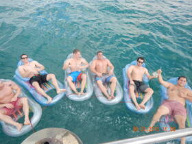 A group of friends relaxes on floating mats in clear turquoise waters, enjoying a fun day on the water together.