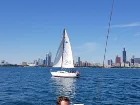 A sailboat glides through the waters of Chicago, with a vibrant city skyline in the background — perfect for a day of sailing and exploration.