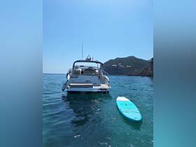 A stunning view of a boat named 'BARCO' anchored in clear waters, with a paddleboard floating nearby, perfect for a day of relaxation and adventure on the sea.