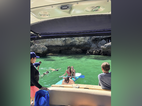 A lively scene with a group enjoying snorkeling and paddleboarding in clear green waters, showcasing the fun and adventure of a day on the boat.